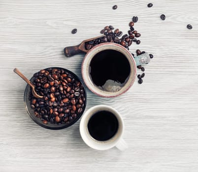 Delicious fresh coffee. Coffee cups and roasted coffee beans on light wood table background. Flat lay.