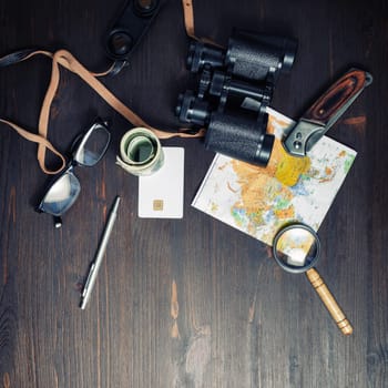 Photo of travel accessories on vintage wood table background. Top view of personal traveler's items. Flat lay.