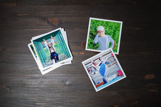 Square photos from a family photo album on wood table background. Flat lay.