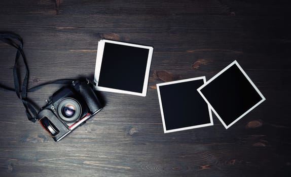 Vintage camera and blank square photo frames on vintage wooden background. For design presentations and portfolios. Flat lay.