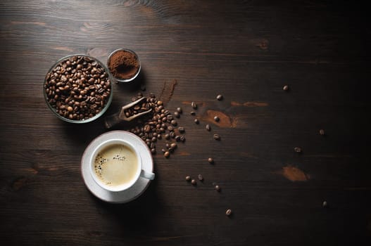 Coffee cup, roasted coffee beans and ground powder on old wooden kitchen table background. Top view. Flat lay.