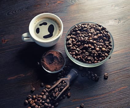 Still life with coffee cup, roasted coffee beans and ground powder on vintage wooden background.