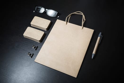 Blank kraft stationery and corporate identity template on black wood background. Responsive design mockup.