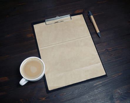 Blank vintage stationery. Clipboard with kraft paper letterhead, coffee cup and pen on wooden background. Responsive design template.