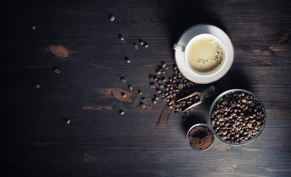 Vintage coffee background. Coffee cup, coffee beans and ground powder on wood kitchen table.. Copy space for your text. Flat lay.