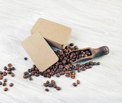 Photo of blank kraft paper business cards and roasted coffee beans on light wooden background. Mockup for your design.