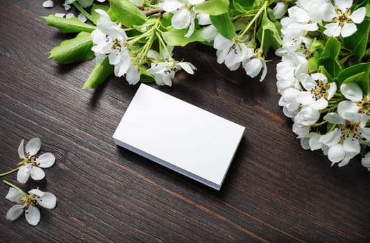 Blank business cards and flowers on wood table background. Mockup for branding identity. Studio shot.