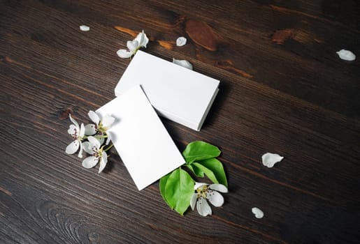 Blank white business cards and flowers on wood table background. Mockup for ID. Template for graphic designers portfolios.