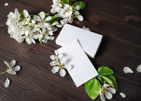 Photo of blank white business cards and flowers on wooden background. Template for ID.