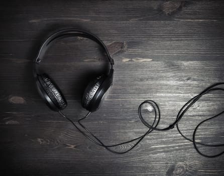 Photo of black headphones on vintage wood table background. Top view. Flat lay.