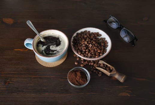Coffee cup and coffee beans on wood table background.