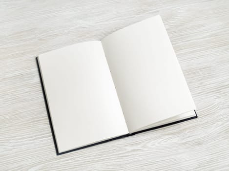 Blank book mock up on light wood table background.