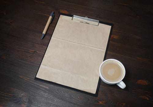 Vintage stationery set. Blank kraft paper, checklist, pen and coffee cup on wood table background.