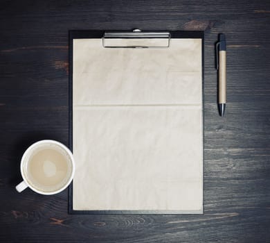 Photo of blank kraft stationery: letterhead, checklist, pen and coffee cup on wooden background. Responsive design mockup. Top view. Flat lay.