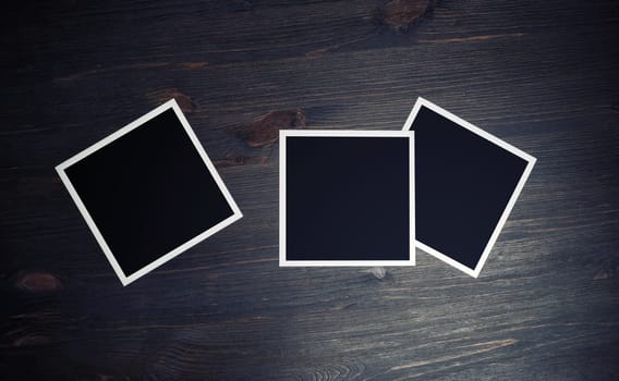 Three blank square photo frames on wood table background. Top view. Flat lay.