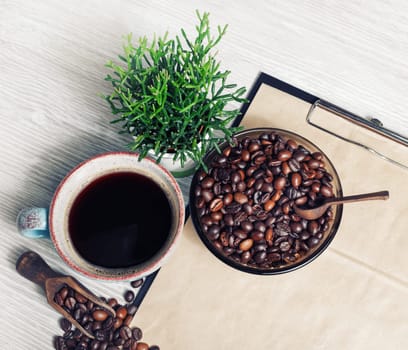 Delicious fresh coffee. Coffee cup, plant and roasted coffee beans.