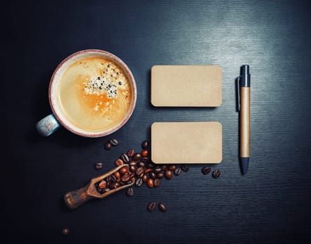 Blank kraft business cards, coffee cup, coffee beans and pen on black wooden background. Flat lay.