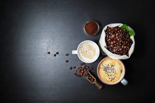 Still life with coffee. Coffee cups and coffee beans in canvas bag on black kitchen table background. Flat lay.
