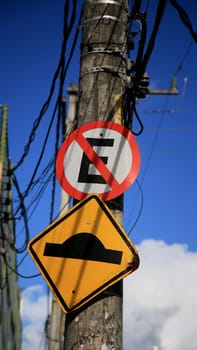 salvador, bahia / brazil - july 4, 2020: traffic signs indicate speed bumps and forbidden to park on a pole attached to the electricity grid in the Cabula neighborhood in the city of Salvador..