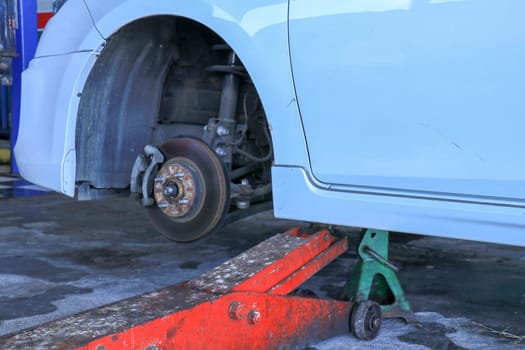 Replacing wheels on a car, jack holds the body in raised position.