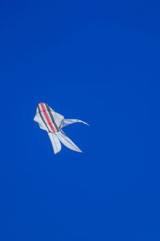 The Balinese white kite with colored strips flies against the blue sky. Blue sky is the perfect background for kites. space for your text.