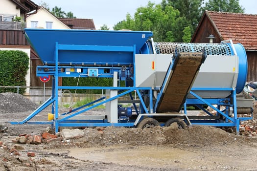 A mobile stone crusher or building rubble shredder for crushing construction material, stones and bricks