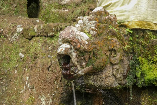 Gargoyles with holy water in the complex of royal tombs of the Udayan dynasty. Ancient royal tombs at Gunung Kawi Temple. Funeral complex centered around royal tombs carved into stone cliffs, Bali.