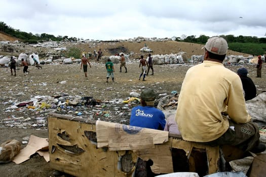itabuna, bahia / brazil - september 22, 2011: waste pickers watch their colleagues playing football at the sanitary landfill in the city of Itabuna.