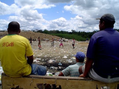 itabuna, bahia / brazil - september 22, 2011: waste pickers watch their colleagues playing football at the sanitary landfill in the city of Itabuna.