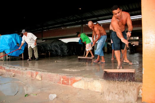 eunapolis, bahia / brazil - june 3, 2009: traders at a street market are seen removing rainwater that fell in the city of Eunapolis.