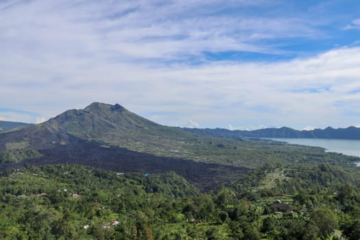 An idyllic view to the top of Mount Batur and the Danau Batur lake. There is a pathway along Batur volcano's rim. Volcanic landscape of Bali, Indonesia. Island hiking. Aerial view at Caldera Batur.