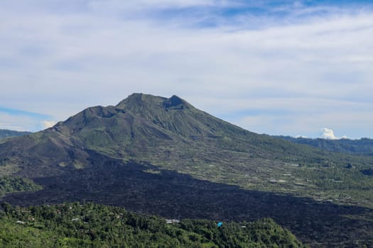 Volcano landscape with lava fields, pine tree forest and farms and houses on the slopes. Kintamani is a village on the western edge of the larger caldera wall of Gunung Batur in Bali, Indonesia.