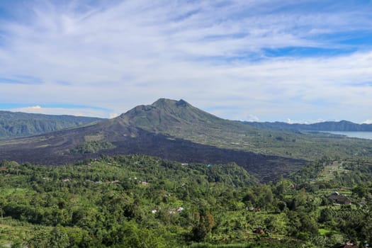 An idyllic view to the top of Mount Batur and the Danau Batur lake. There is a pathway along Batur volcano's rim. Volcanic landscape of Bali, Indonesia. Island hiking. Aerial view at Caldera Batur.