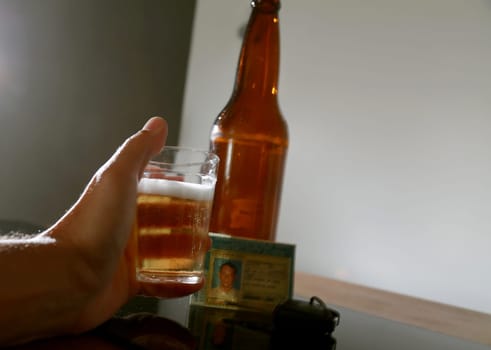 salvador, bahia / brazil - June 29, 2015: Beer bottle on bar table next to a driver's license and vehicle key, symbolizing drink consumption by vehicle drivers.