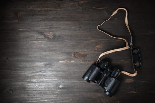 Black military binoculars on wooden background. Lot of copy space for your text. Flat lay.