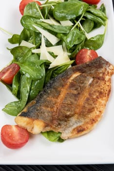 Grilled Dorado fish fillet with spinach, tomato and cheese