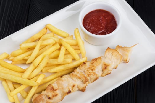 Grilled chicken meat with fried potatoes on white plate