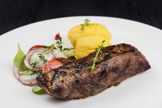 Grilled beef meat with potato and vegetables on white plate