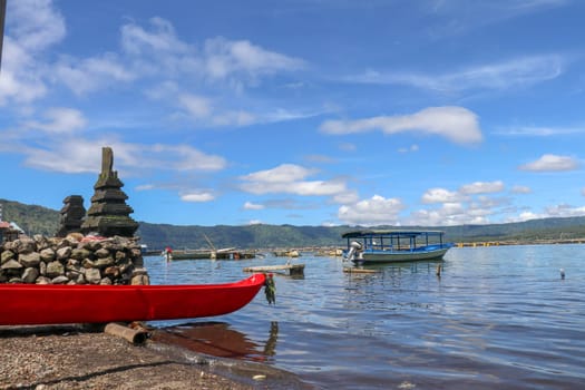 Boat traveling on the lake near the Trunyan Village of Bali. Life of Trunyan Village at Batur Lake and Volcano, Kintamani, Bali, Indonesia. This village is one of culturally isolated Bali Aga village.