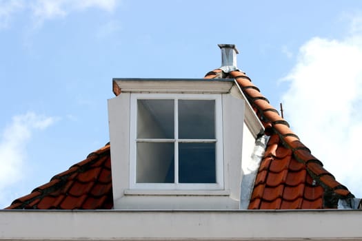 A skylight on red tiled roof, blue sky in the background.