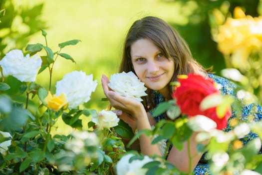 portrait of a smiling girl against the backdrop of roses in the park