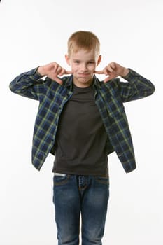 boy on a white background in a plaid shirt blows his cheeks with his fingers