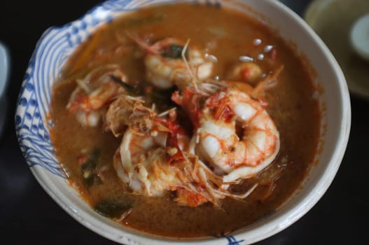 Tom Yum Goong Spicy Sour Soup or River prawn spicy soup on wood table . Thai food