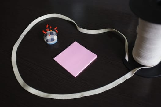 Set of tailoring tools and accessories on a black wooden background. Space for text