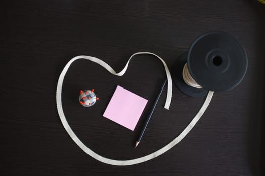 Set of tailoring tools and accessories on a black wooden background. Space for text