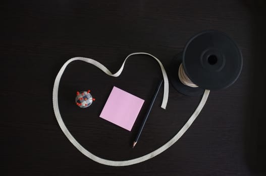 Set of tailoring tools and accessories on a black wooden background. Space for text