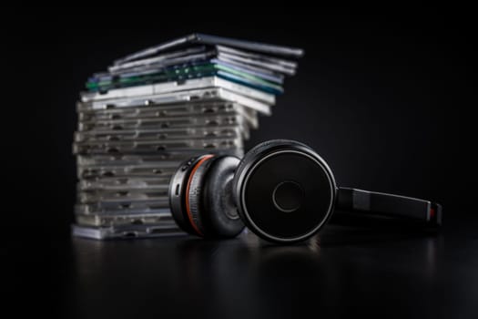 Hi-Fi headphones on stack of CDs on black background with copy space.