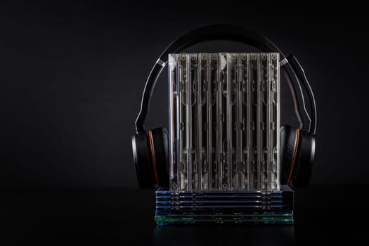 Hi-Fi headphones on stack of CDs on black background with copy space.