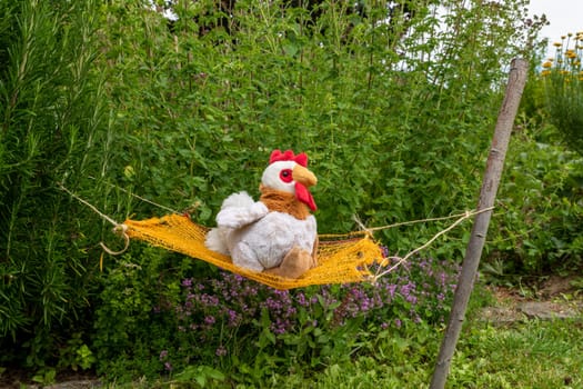 White soft toy lies in a hammock between green bushes in a meadow