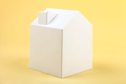 White plastic model house on yellow background